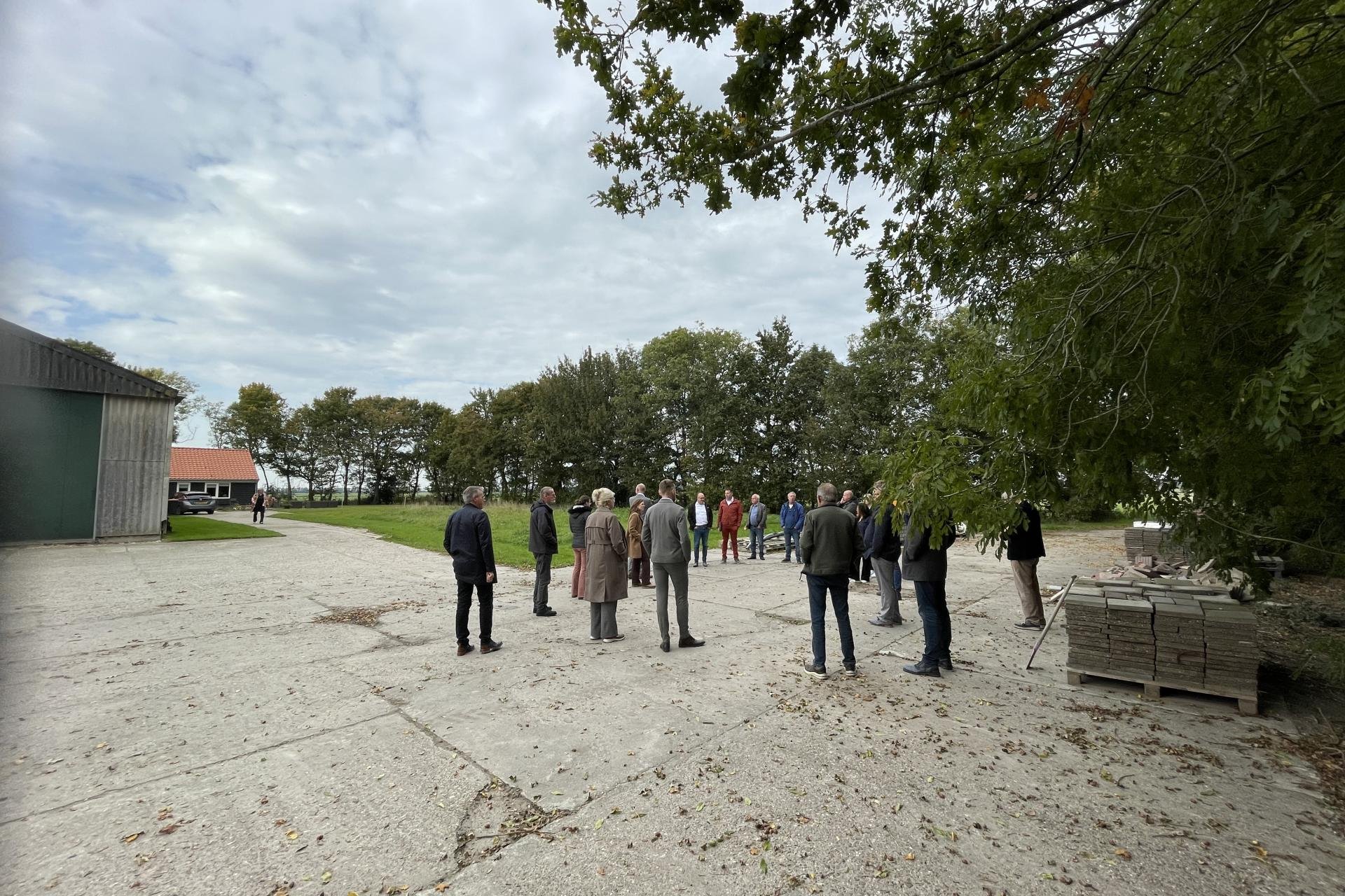 Een groep mensen staat in een kring op een boerenerf.